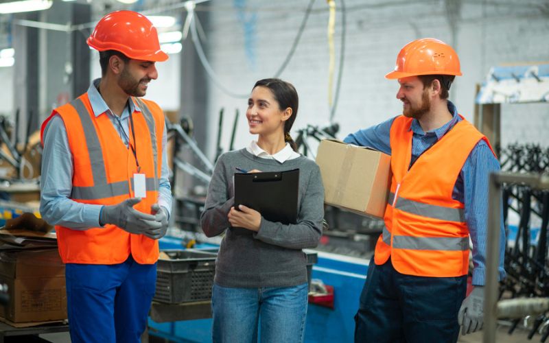 Three workers wearing safety vests communicate with each other at an industrial training institute in Kolkata.